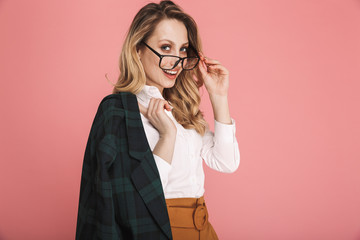 Portrait of gorgeous blond woman 30s in stylish outfit touching eyeglasses and looking on camera