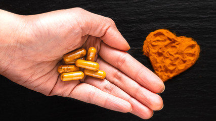 Health care concept Turmeric spices capsule in the hand in black background