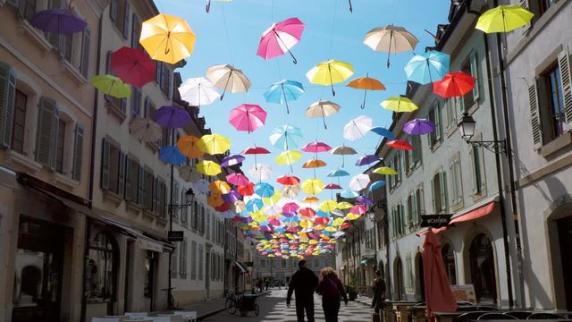 Geneva, Switzerland - 03/03/2019: A modern brightly colored street art installation in the town of Geneva, Switzerland. Brightly colored umbrellas hang above a modern urban street.