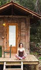 A woman is sitting on the porch of an old wooden house.