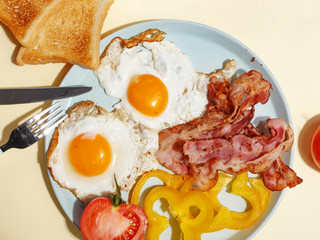 Simple breakfast. Fried egg with bacon, bell pepper and toast on a plate.