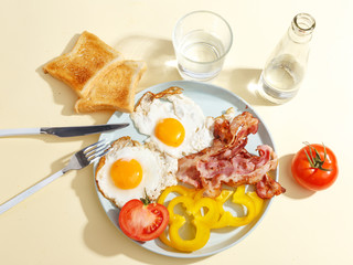 Simple breakfast. Fried egg with bacon, bell pepper and toast on a plate.