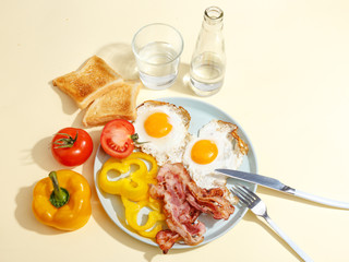 Simple breakfast. Fried egg with bacon, bell pepper and toast on a plate.
