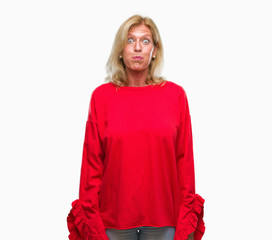Middle age blonde woman over isolated background puffing cheeks with funny face. Mouth inflated with air, crazy expression.