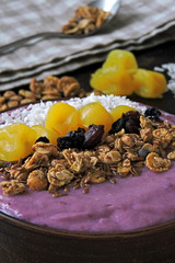 A colorful healthy breakfast of purple smoothies with granola and dried fruit.
