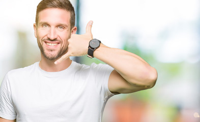 Handsome man wearing casual white t-shirt smiling doing phone gesture with hand and fingers like talking on the telephone. Communicating concepts.