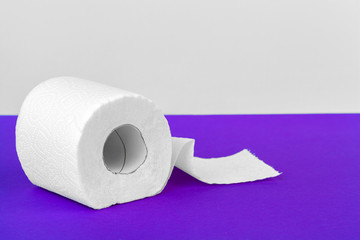 Toilet paper rolls isolated on white table with purple background