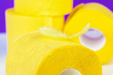 Minimalistic composition of bright yellow toilet paper rolls on purple background