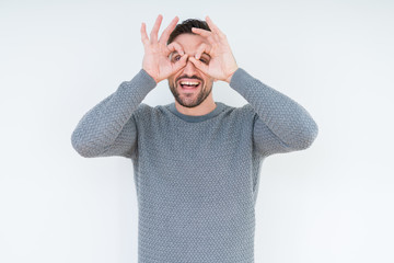Young handsome man wearing casual sweater over isolated background doing ok gesture like binoculars sticking tongue out, eyes looking through fingers. Crazy expression.