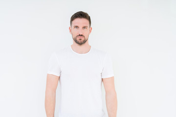 Young handsome man wearing casual white t-shirt over isolated background Relaxed with serious expression on face. Simple and natural looking at the camera.