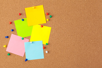 Cork board with several colorful blank notes with pins