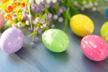 Easter eggs and flowers on gray wooden planks
