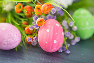 Easter eggs and flowers on gray wooden planks