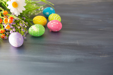 Easter eggs and flowers on gray wooden planks