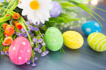 Easter eggs and flowers on gray wooden planks