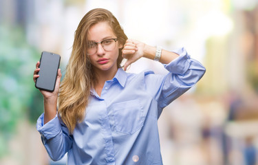 Young beautiful blonde business woman showing screen of smartphone over isolated background with angry face, negative sign showing dislike with thumbs down, rejection concept