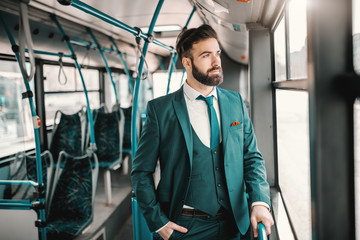 Young Caucasian businessman in turquoise suit driving in public bus and looking trough window. Don't quit.