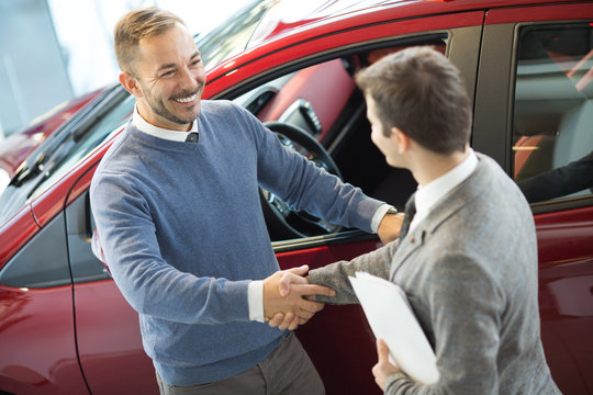 Male customer and car salesman at the dealership
