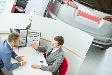 Male customer and car salesman at the dealership
