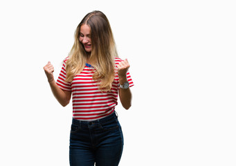 Obraz na płótnie Canvas Young beautiful blonde woman over isolated background very happy and excited doing winner gesture with arms raised, smiling and screaming for success. Celebration concept.