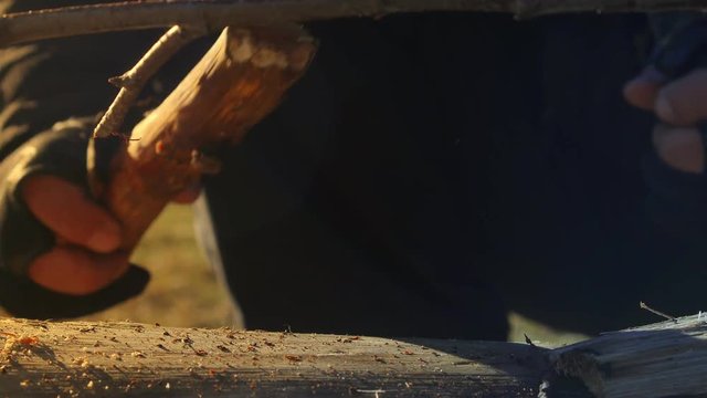 hands of a man close-up who cuts wood to start a fire with a knife.