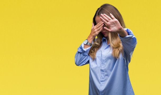 Young beautiful blonde business woman wearing glasses over isolated background covering eyes with hands and doing stop gesture with sad and fear expression. Embarrassed and negative concept.