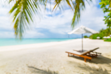 Blurred sunbeds on beautiful beach in resort, palm leaf and sea view under blue sky with clouds