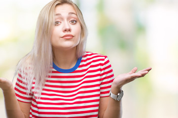 Young blonde woman over isolated background clueless and confused expression with arms and hands...