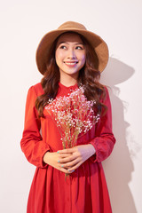 a lovely young woman in summer dress and straw hat posing while holding bouquet flowers