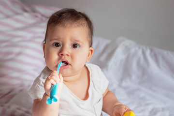 Baby girl Brushing Teeth on bed, light background, close-up, portrait