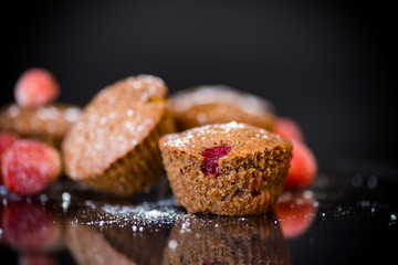 fresh sweet muffins with berries inside on black