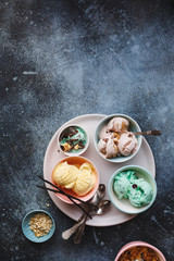 Various types of ice cream in pastel colored bowls. Top view, blank space, rustic background 