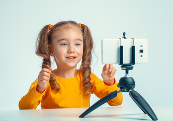beautiful cute little blogger girl recording a video with smartphone