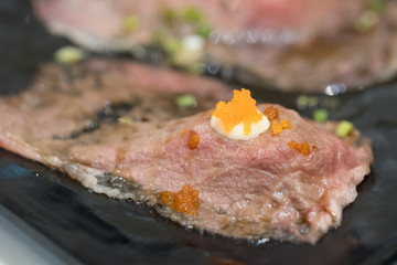 Grilled Wagyu beef sushi with fish roe on black plate