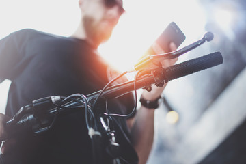 Bearded muscular tattooed hipster in sunglasses using smartphone after riding by electric scooter in the city. Innovative transport