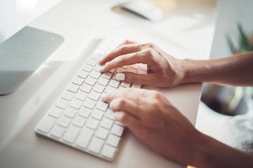Fototapeta na wymiar Female hands typing on desktop computer keyboard in modern working place at coworking office.Blurred background