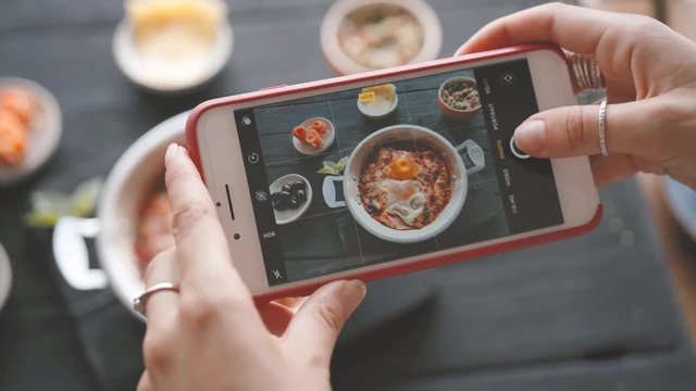 Female hands take photos of food by modern smartphone. Closeup. 4K.