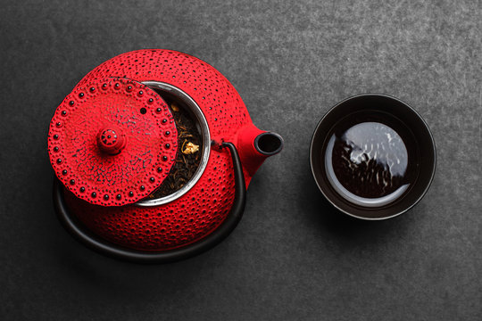 Tetera roja de hierro fundido y taza de t&eacute; vista de arriba sobre pizarra negra
