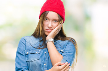 Young caucasian beautiful woman wearing wool cap over isolated background thinking looking tired and bored with depression problems with crossed arms.