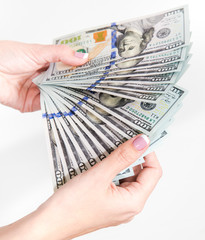 Closeup view of female hands holding many 100 dollars banknotes. Color photography.