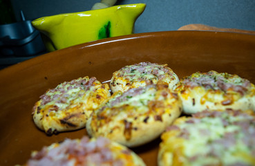 SMALL PIZZAS IN A ROLLED PLATE IN A KITCHEN TABLE