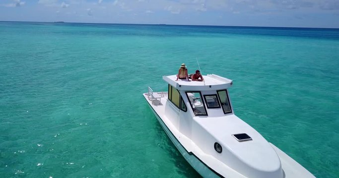 Man and woman lay on roof of speed boat, Pan around empty blue ocean 4k