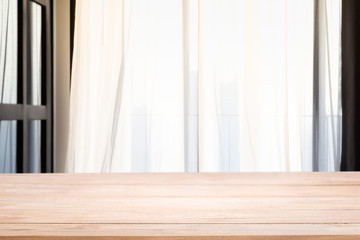Empty wood table top with Defocused of curtain window in living room with sunlight..