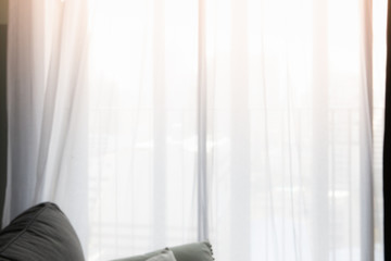 Blur of curtain window and pillow in living room with sunlight in the morning.