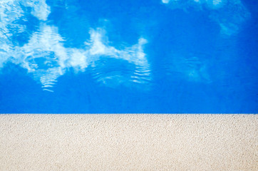 Closeup view of the swimming pool edge with blue water copy space during a sunny summer day