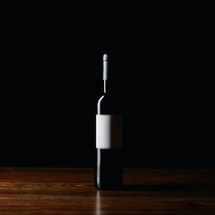 Wine bottle with blank label on wooden surface isolated on black