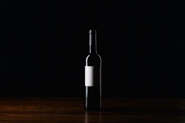 Fototapeta na wymiar Wine bottle with blank label on wooden surface isolated on black