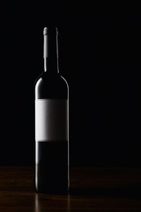 Wine bottle with blank label on wooden surface
