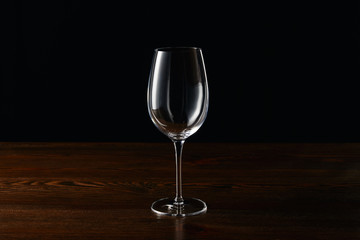 Empty wine glass on wooden surface isolated on black