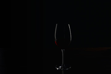Silhouette of glass of burgundy red wine on black